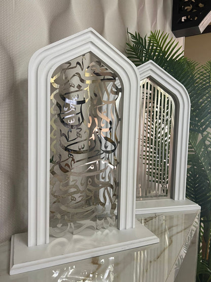 Decorative white arch with intricate cut-out design on a reflective surface.