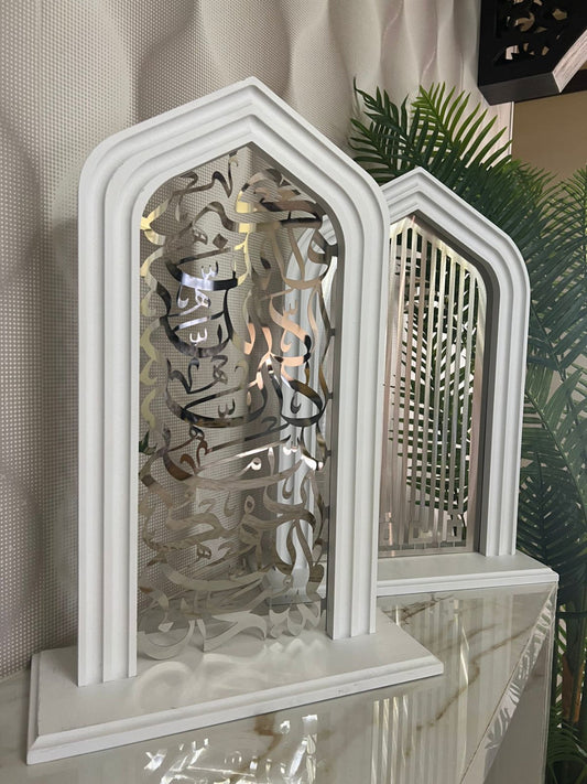 Decorative white arch with intricate cut-out design on a reflective surface.