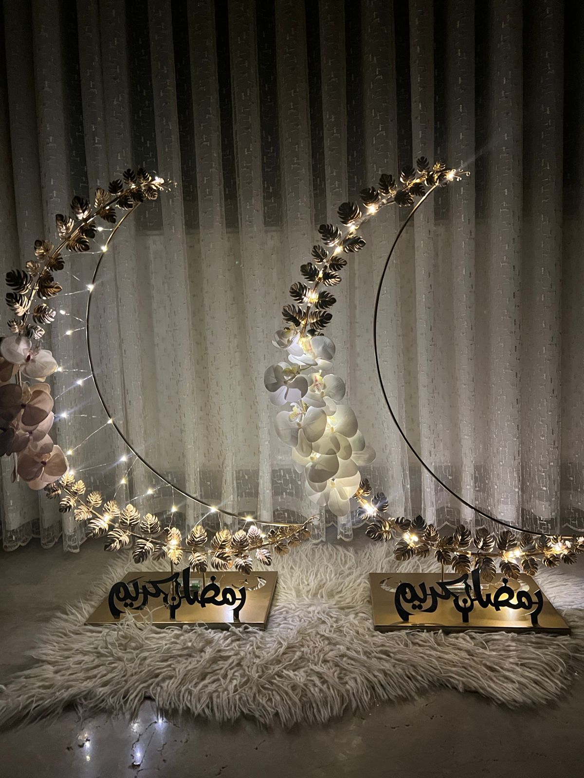 Decorative crescent moon with lights on a fluffy rug against a curtain background