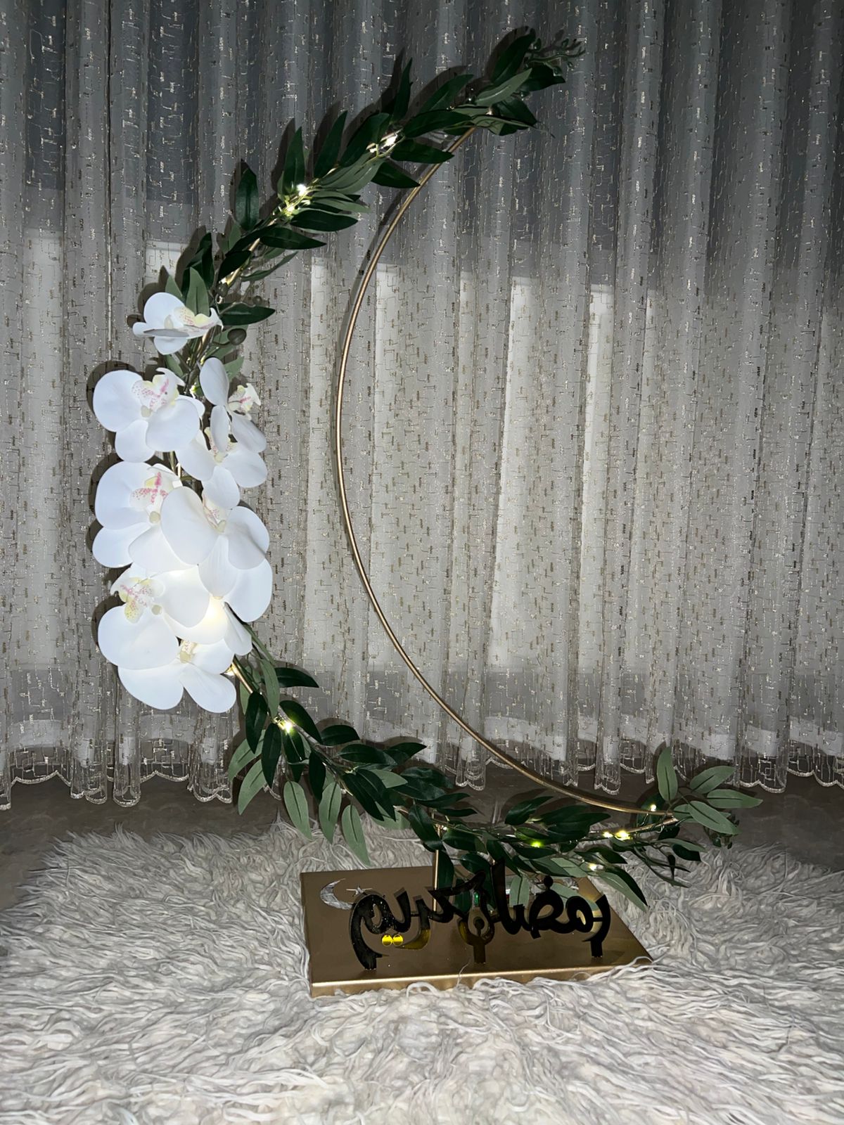 Decorative wreath with white flowers and green leaves on a textured surface