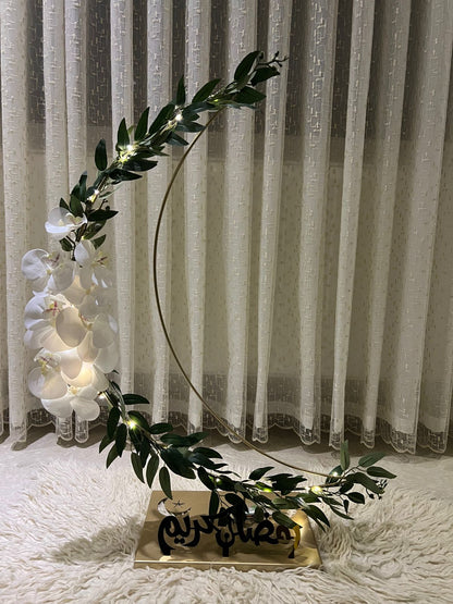 Decorative arch with greenery and white flowers against a curtain background
