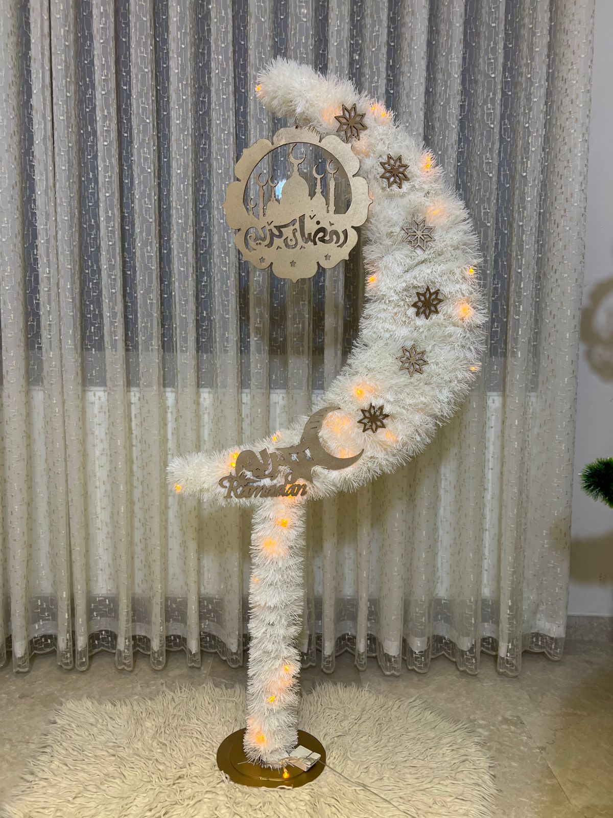 Decorative white wreath with lights and metal cutout against a striped curtain background