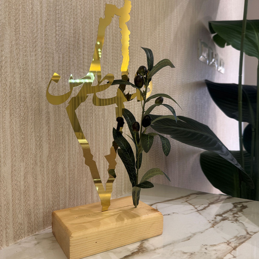 Gold decorative item with plant on a marble surface