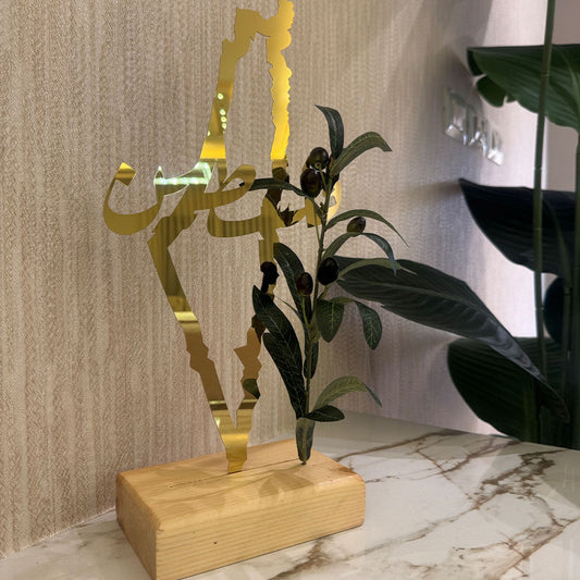 Gold decorative item with plant on a marble surface